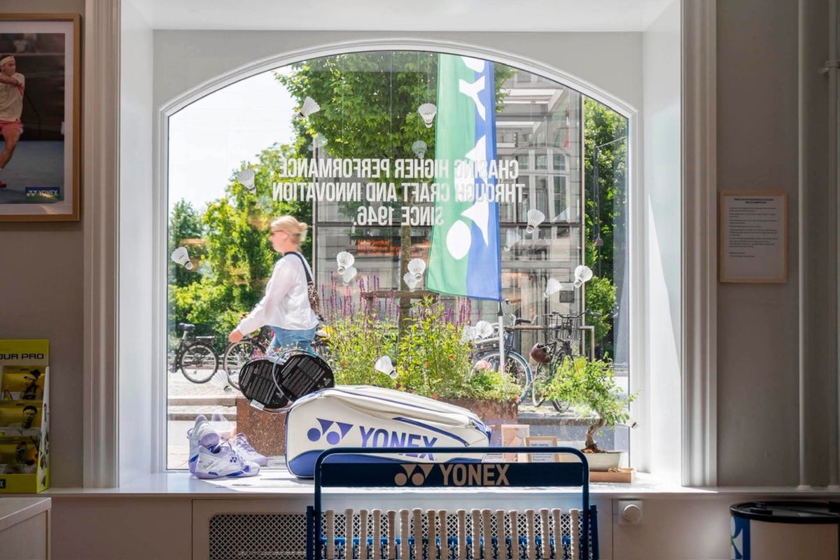 Inde i Yonex Store Copenhagen — Yonex bag ved bonsai og arched window